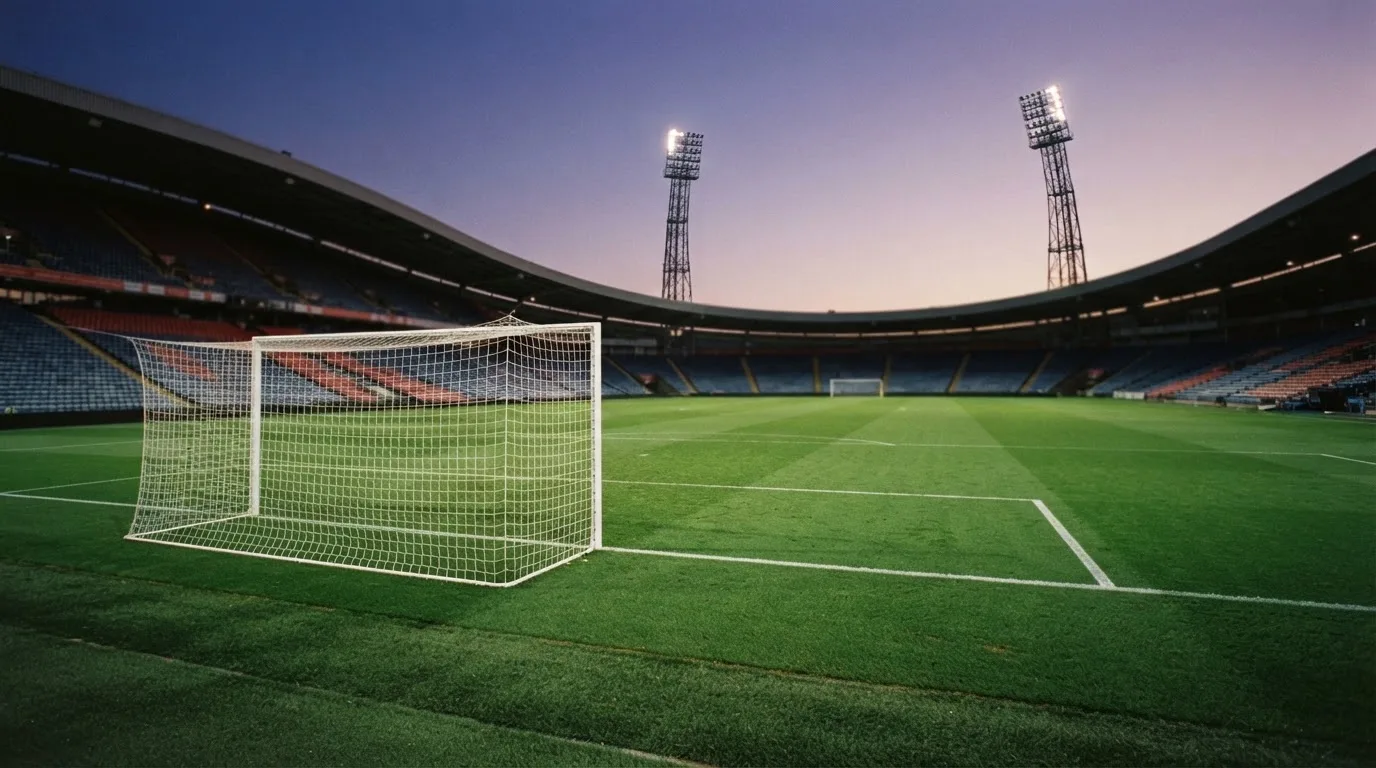 An empty football stadium with floodlight masts at dusk