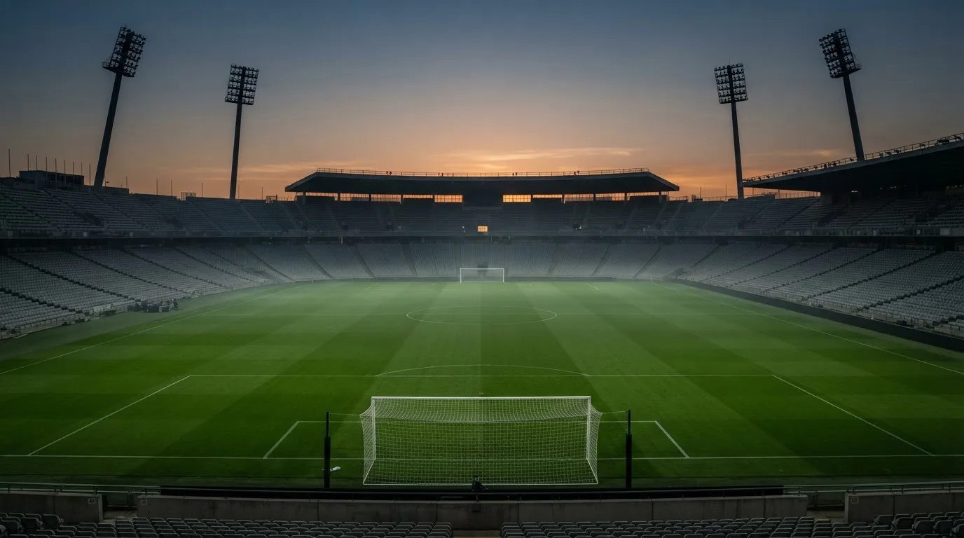 An empty football stadium with floodlight masts at dusk