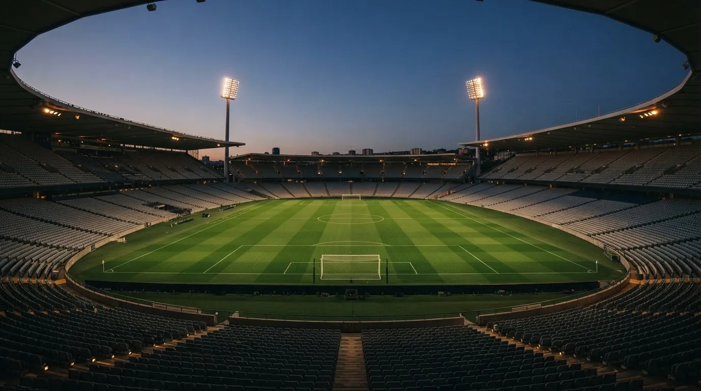 An empty football stadium with floodlight masts at dusk