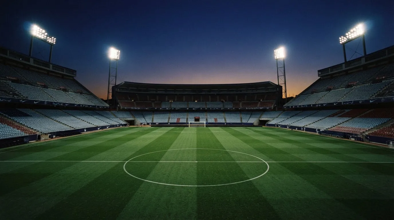 An empty football stadium with floodlight masts at dusk