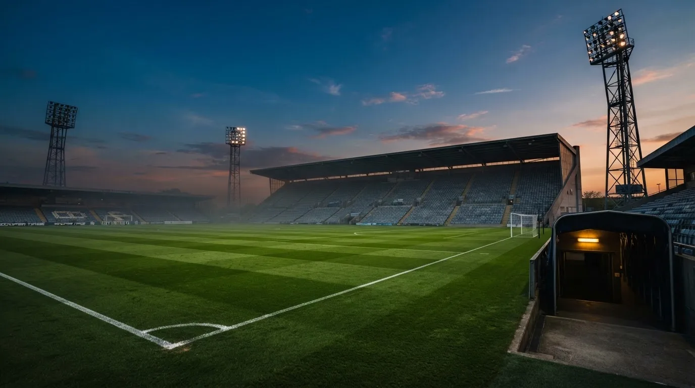 An empty football stadium with floodlight masts at dusk