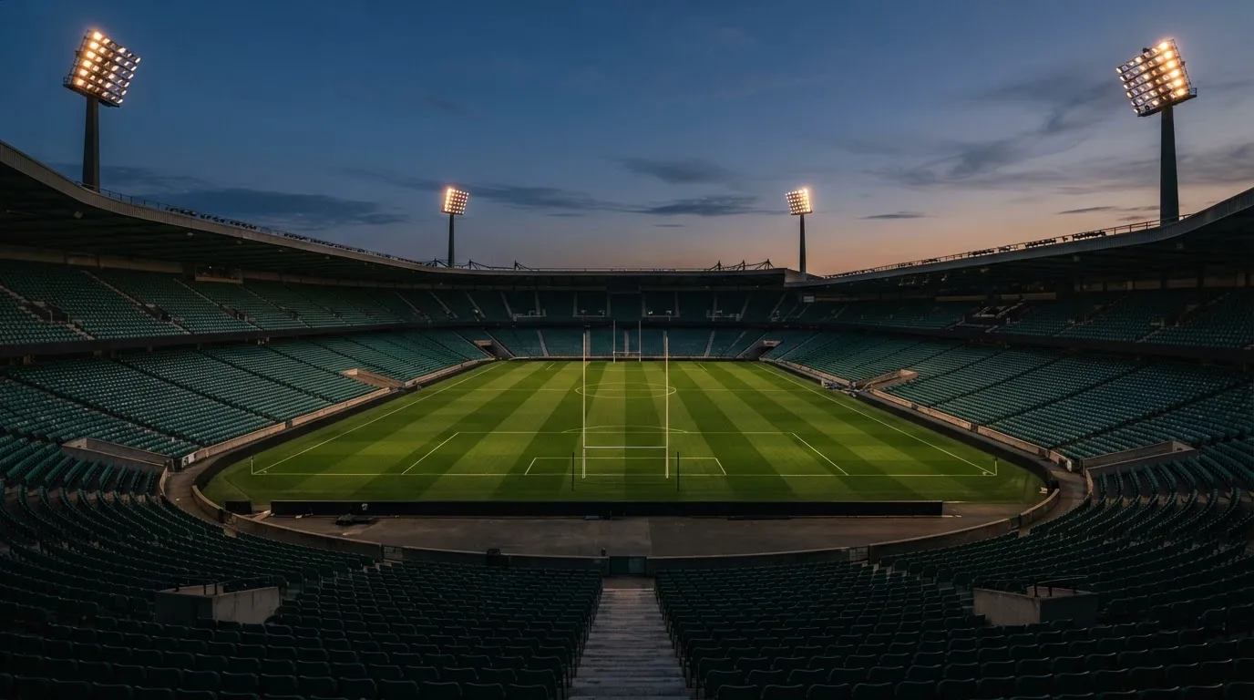 An empty football stadium with floodlight masts at dusk