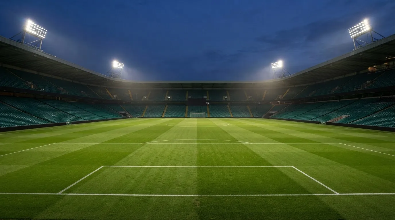 An empty football stadium with floodlight masts at dusk