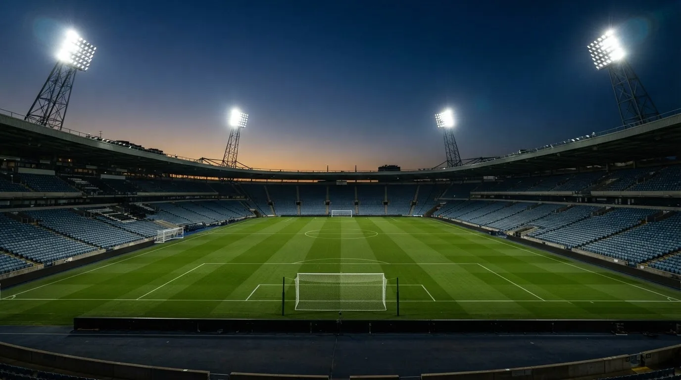 An empty football stadium with floodlight masts at dusk