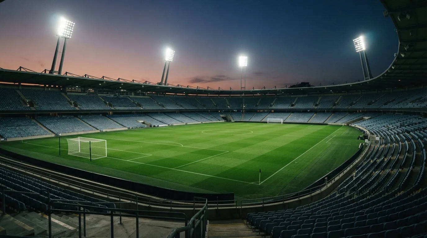 An empty football stadium with floodlight masts at dusk