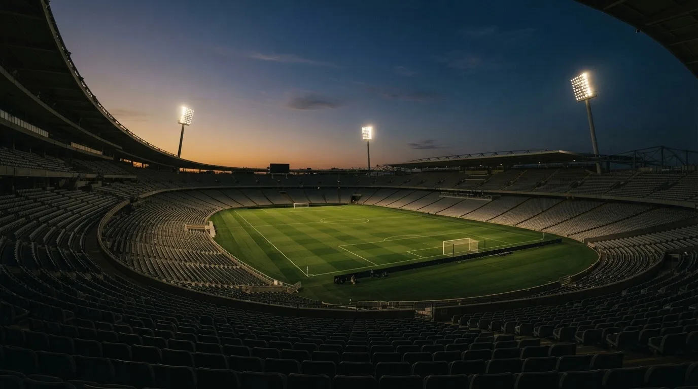 An empty football stadium with floodlight masts at dusk