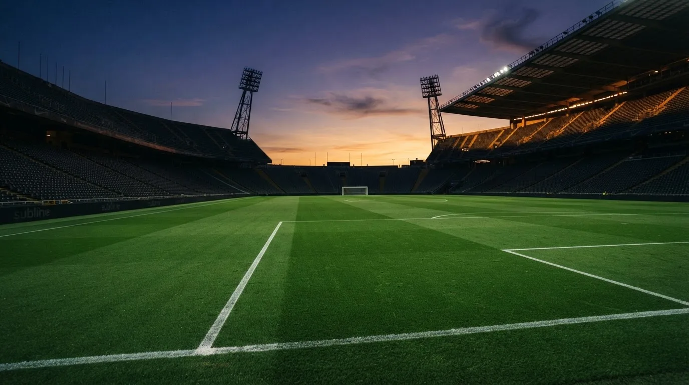 An empty football stadium with floodlight masts at dusk