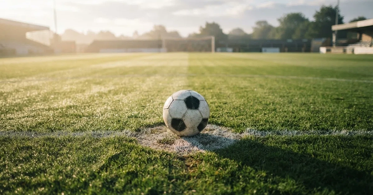 A ball on the centre spot of a grass pitch in morning light