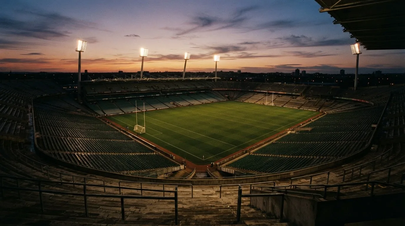 An empty football stadium with floodlight masts at dusk
