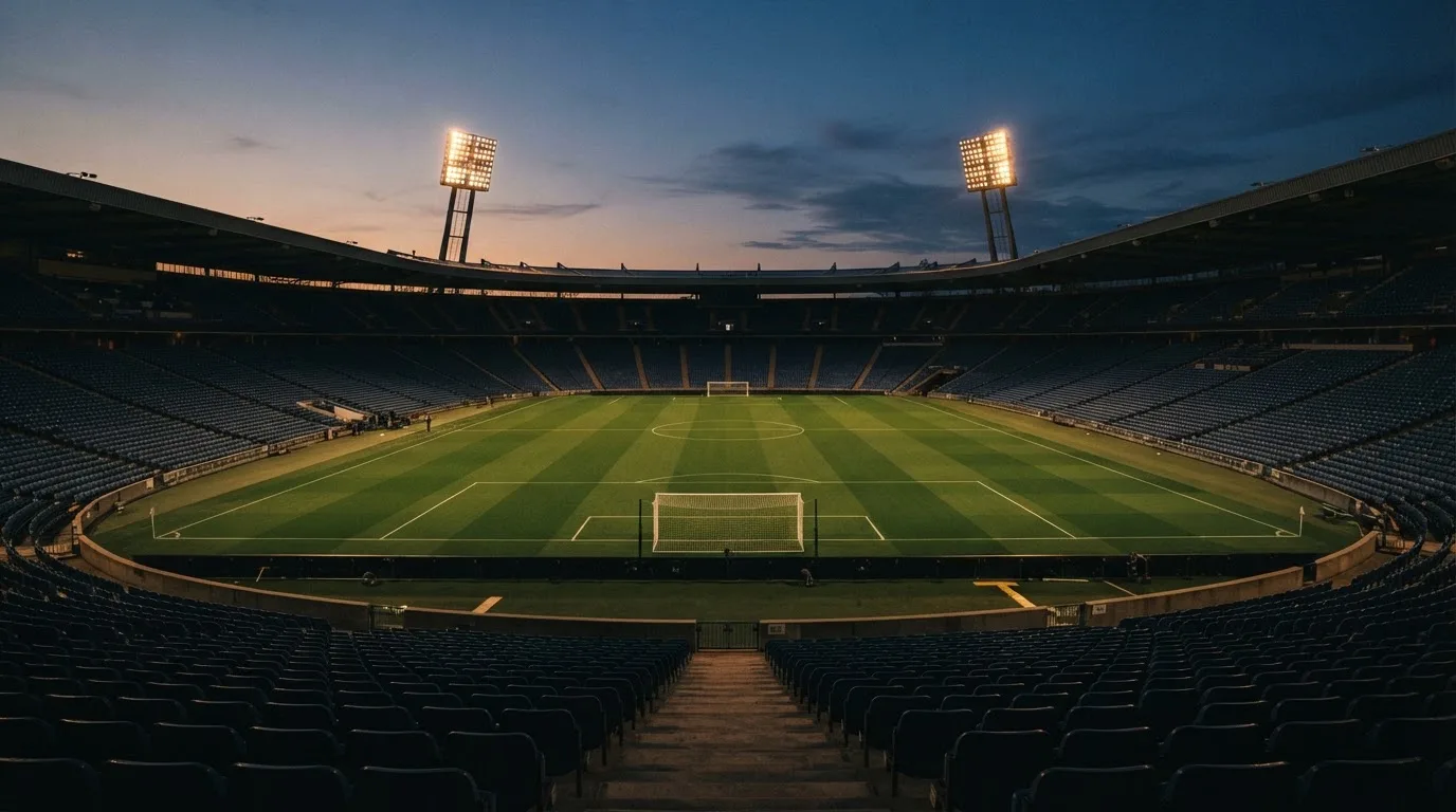 An empty football stadium with floodlight masts at dusk
